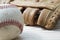 Old worn leather baseball glove and used ball on a wooden table