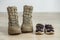 Old worn military boots and children`s shoes on wooden floor. Concept of military father and family