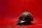 Old worn military helmet on red surface