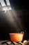 Old worn red bucket standing in a foggy environment on the attic. Red bucket lit by a ray of light from the attic window