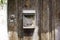 An old, worn, rusted and unlabeled mailbox, mounted on an old weathered wooden door. Next to it is an unlabeled bell