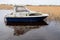 Old worn small fishing boat on a calm water in a lake. Cloudy sky. Nobody. Small river vessel. Hobby and transportation concept