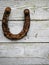 Old worn steel horse shoe on a white wooden background, symbol of luck