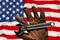 Old and worn work glove holding wrench over US American flag,. American labor, work, and employment concept