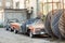 Old wrecked covered car at back yard of workshop. Abandoned convertible vehicle under black curtain near garage doors. Recycling a