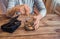 Old wrinkled hands holding jar with coins, wooden background.