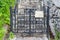 Old wrought iron gate with crosses, covered with black paint and rust, leading to the old staircase up along the wall