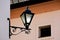 Old wrought iron street light lantern. ornate retro stile lamp. stucco facade.