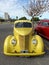 Old yellow 1937 Ford V8 coupe 5 window street rod in a parking lot.