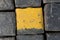 Old yellow and black granite road cubes or cobbles as background or wallpaper. Vertical image.