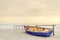 Old yellow blue wooden boat on white beach on warm sunset