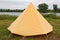 Old yellow canvas camping tent with iron pegs
