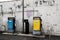 Old yellow diesel pump and old blue gasoline pump in front of old white brick wall