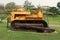 Old yellow rusty crawler tractor in the field. Old crawler tractor on green garden