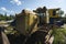 Old yellow rusty tractor in field in sunny day.