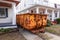 An old yellow scraped up dumpster in a driveway between two very close houses