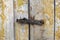 Old yellow shabby door closed with rusty hook