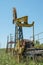 An old yellow stopped oil rig in a field against a blue sky. A concept of the decline of the oil industry. Oil ran out