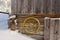 Old yellow wagon wheel hanging on wall to decorate rustic wooden