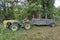 Old yellow wheeled tractor refashion for agriculture with wooden cart on the field, town Delchevo