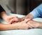 Old and young holding hands on light background, closeup. Care is at home of elderly