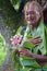 Olde aged Pacific Islander man looks at exotic flower on eco tourism tour in Rarotonga Cook Islands