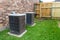 Older air conditioner units next to brick home with copy space