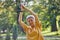 Older Asian woman makes stretching exercises in summer park