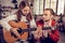 Older brother helping his cute teenage sister playing the guitar