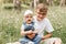 Older brother holds little sister in the park in the summer