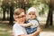 Older brother holds little sister in the park in the summer