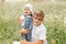 Older brother holds little sister in the park in the summer