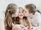 The older brother and older sister kiss the little sister on both cheeks. The concept of happy moments is the children of this