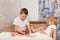 Older brother tickles younger sister`s bare feet on bed at home