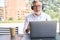 Older business man wears headphones looking at laptop having hybrid remote call.