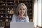 Older businesswoman sit at desk with laptop posing for camera