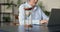 Older businesswoman work on laptop, hourglass on table, closeup view