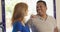 older Caucasian and African American couple standing in their kitchen smiling