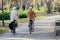 Older Caucasian couple riding bicycles through public park together. Back view