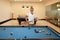 Older caucasian men, white beard and white hair in white shirt looking at billiard or snooker ball with concentration and serious