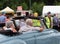 An older couple driving past rotary club volunteers in the public park at hebden bridge annual vintage weekend