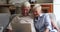 Older couple use laptop make videocall seated on sofa