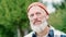 Older elder hipster man standing in nature park wearing earbud. Portrait