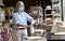 Older female entrepreneur wearing mask using sanitizer working in warehouse.