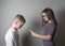 Older girl scolding younger boy on gray background