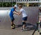 Older girl teach younger boy how to ride a  skateboard. Skateboard lesson