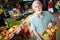 Older happy male purchaser holding basket with fruits and vegetables