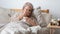 Older ill woman holding handkerchief blowing nose in bed