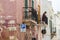 Older local woman looking to street from balcony in Polignano a Mare, Italy