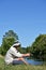 Older Male Fisherman Sitting With Rod And Reel Outdoors